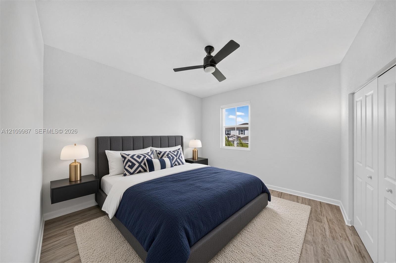 Staged bedroom, porcelain flooring, ceiling fan with integrated lighting, and dual bi-fold closet doors