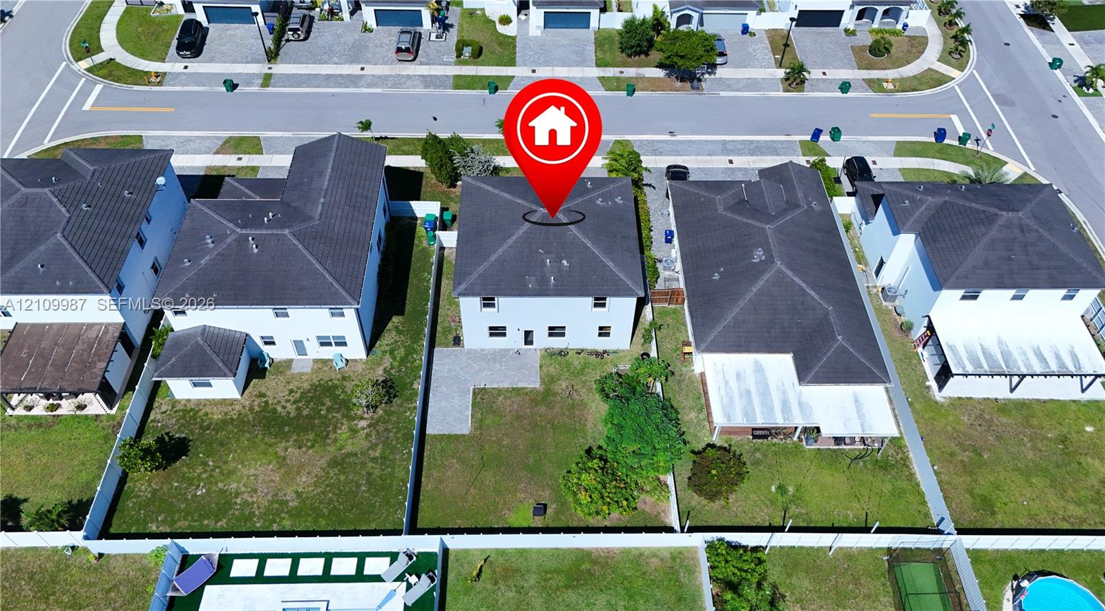Two-story residential property featuring a tile roof, light-toned exterior finish, a stone-paved patio area, and a fully fenced backyard
