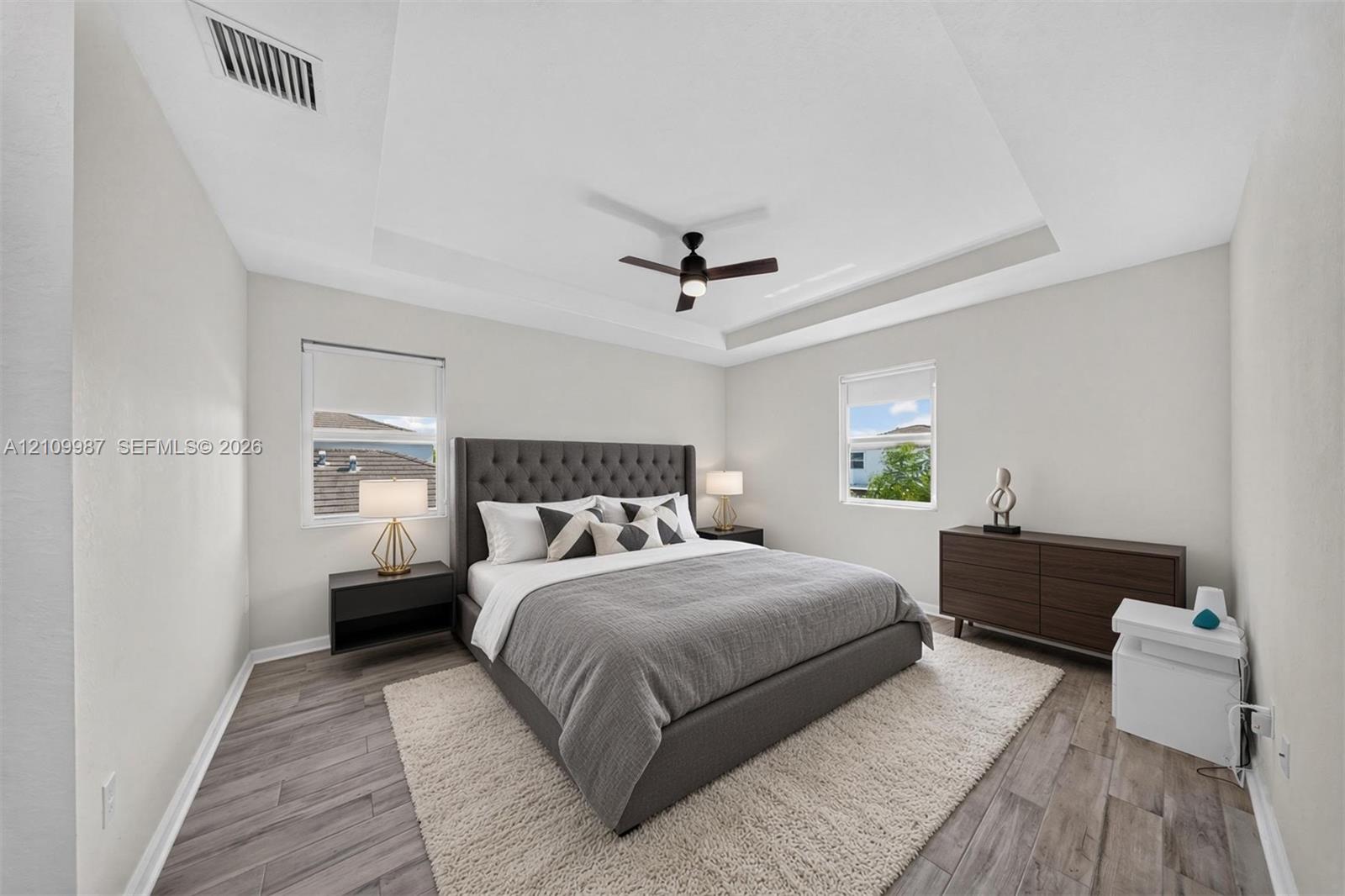 Tray ceiling, porcelain flooring, and a central ceiling fan with integrated lighting