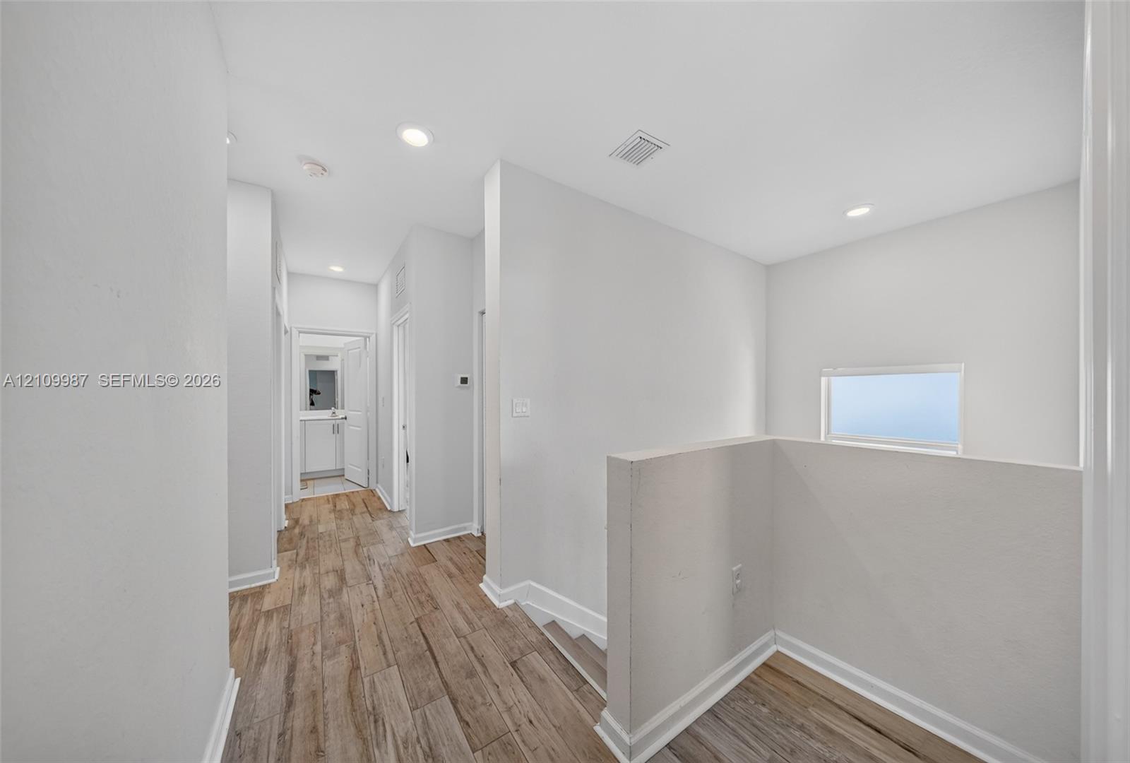 Hallway featuring porcelain flooring, recessed lighting, and a half-wall partition