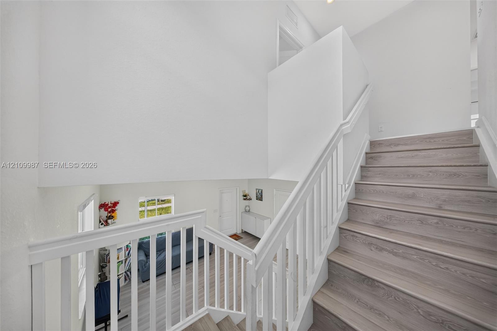 Staircase featuring vinyl floor, white balusters, and a matching handrail
