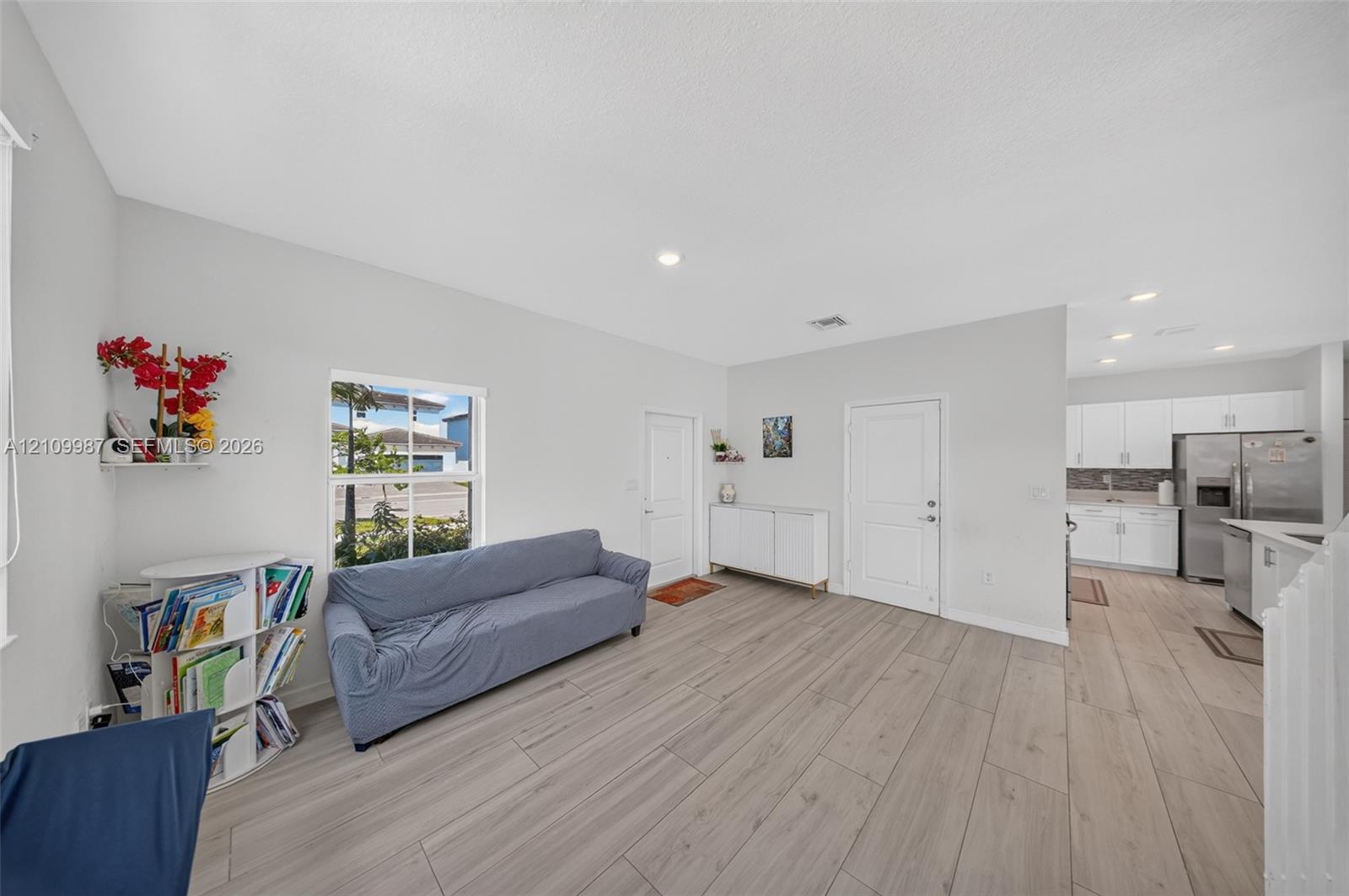 Open floor plan featuring porcelain-finish flooring, recessed lighting, and white cabinetry