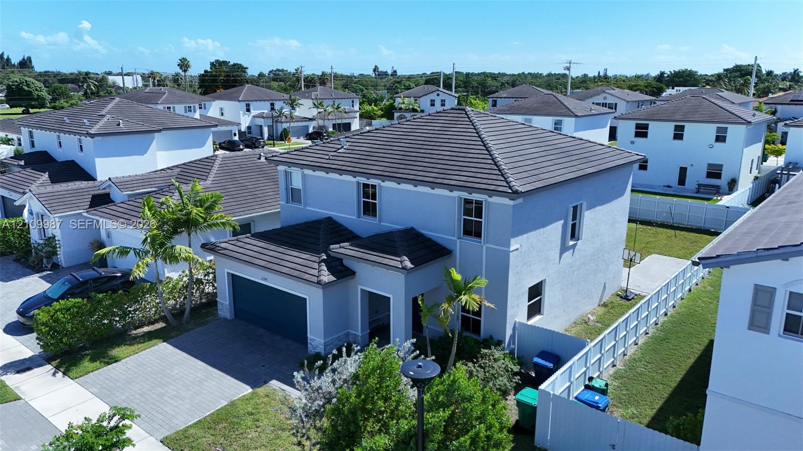 Two-story exterior featuring a hip roof with flat tile, stucco siding, and a paved driveway