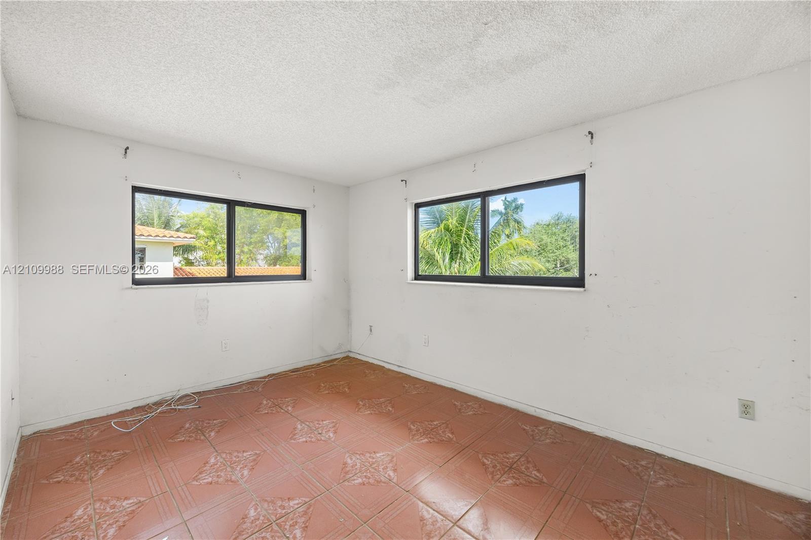 Interior room featuring tile flooring with decorative detailing and two horizontal sliding windows with dark frames Interior room featuring tile flooring with decorative detailing and two horizontal sliding windows with dark frames