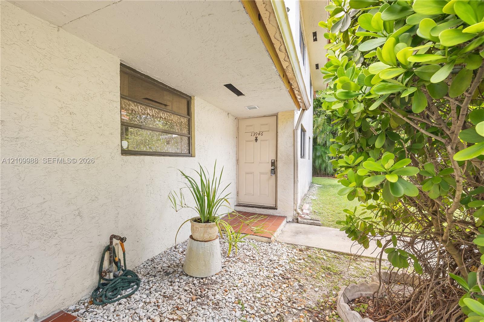 Stucco exterior featuring a recessed entry, multi-pane window, tiled landing, and decorative gravel hardscaping