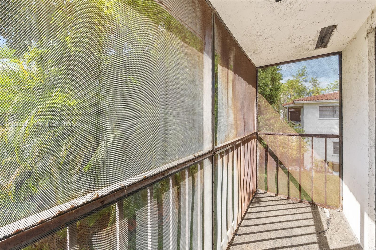 Screened balcony featuring concrete flooring and metal railings