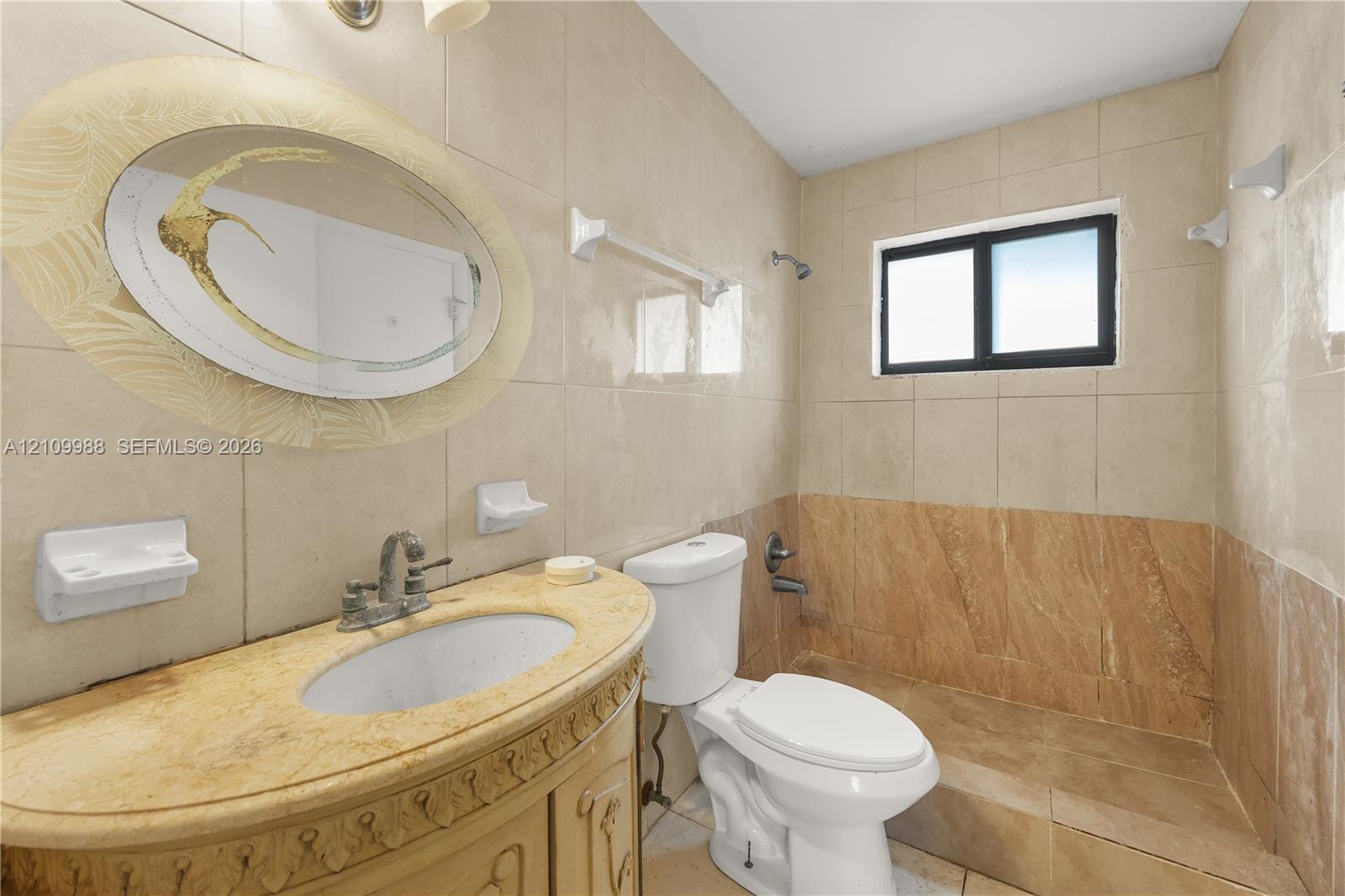 Bathroom featuring neutral tile wall cladding, a vanity with a stone countertop and undermount sink, and a built-in shower enclosure