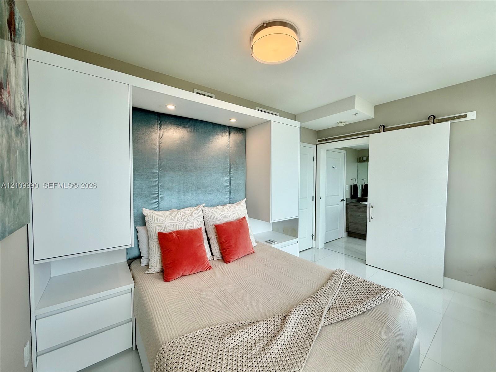 Built-in white cabinetry with recessed lighting, integrated blue accent wall paneling, sliding door hardware, and polished tile flooring