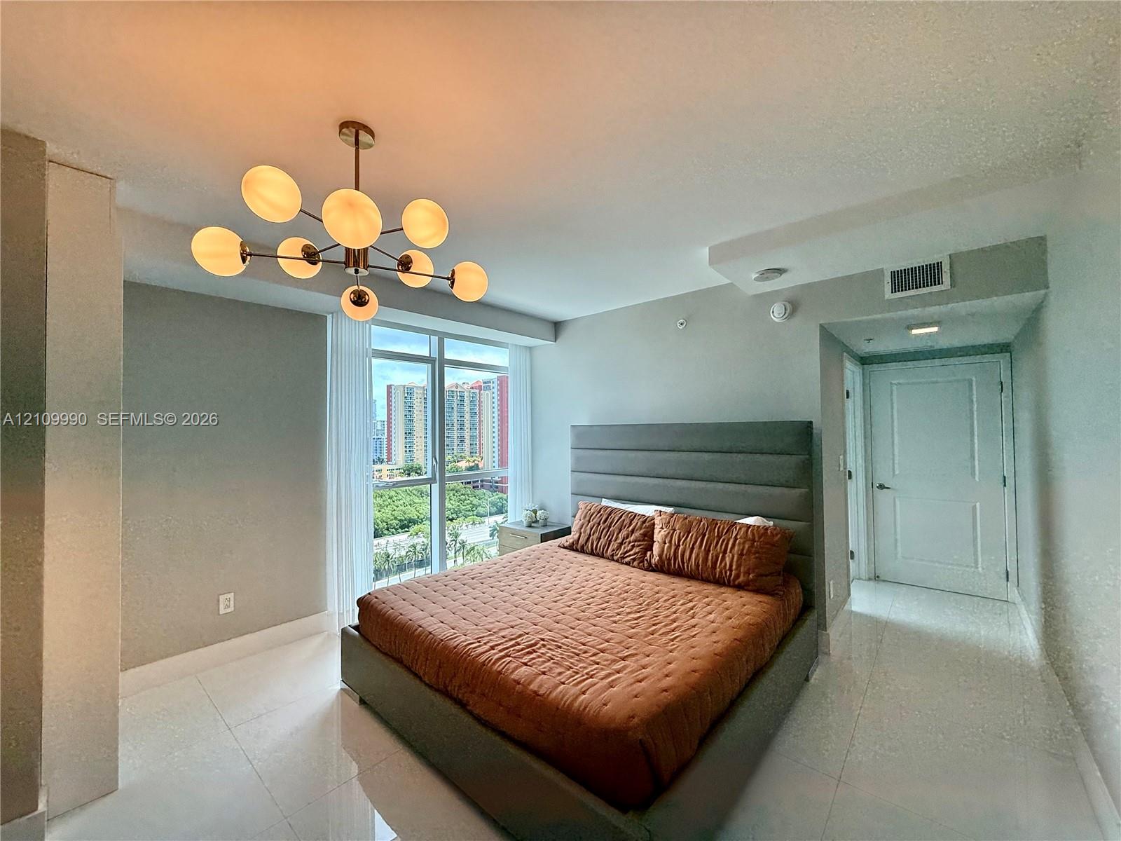 Floor-to-ceiling windows, polished tile flooring, contemporary multi-bulb chandelier, and crisp neutral wall finish
