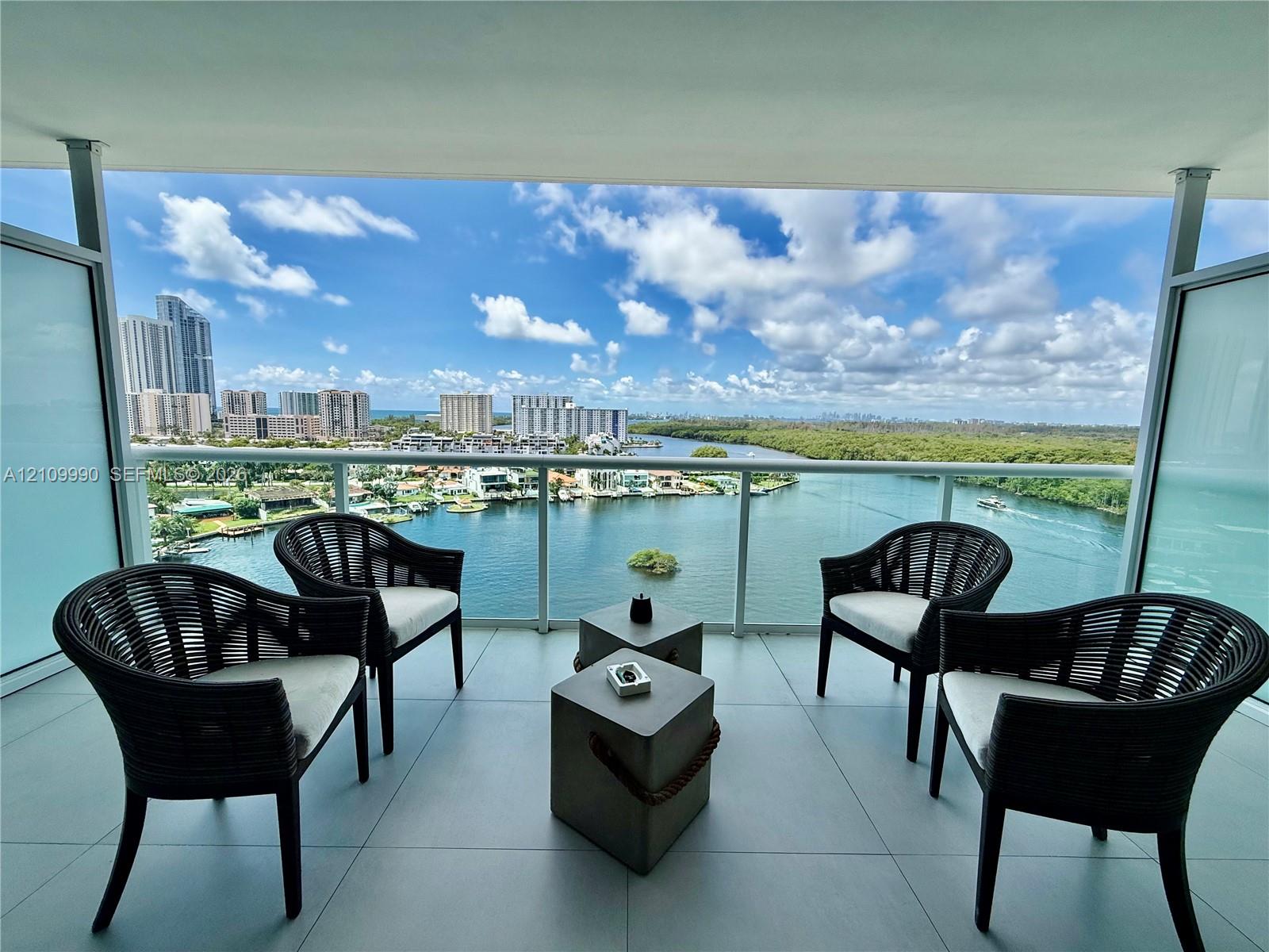 Private balcony featuring large-format tile flooring and a glass railing enclosure, showcasing expansive water and coastal horizon scenery