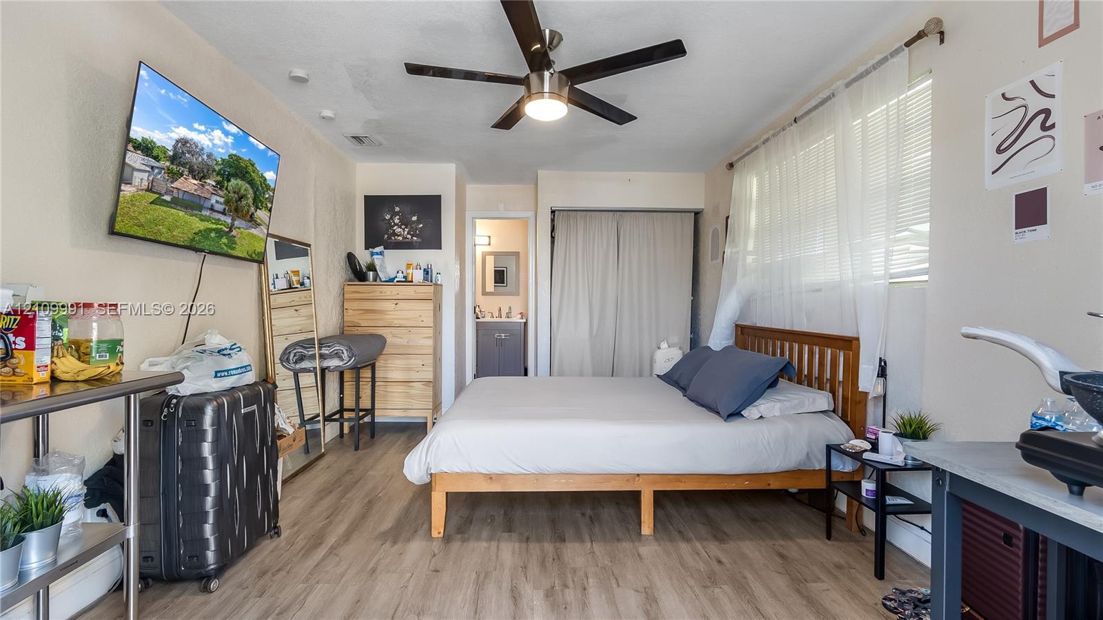 Neutral-toned room featuring wood-finish flooring, a ceiling fan with integrated lighting, and a closet with sliding doors