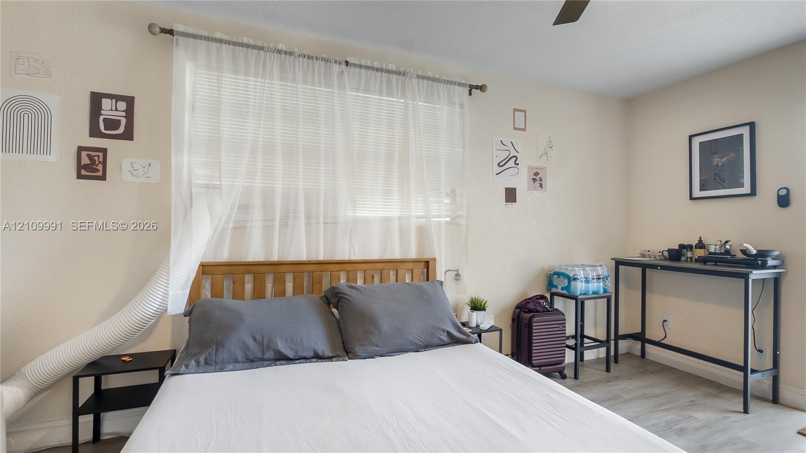 Interior space featuring wood-finish flooring, a horizontal window with adjustable blinds, and a ceiling-mounted fan