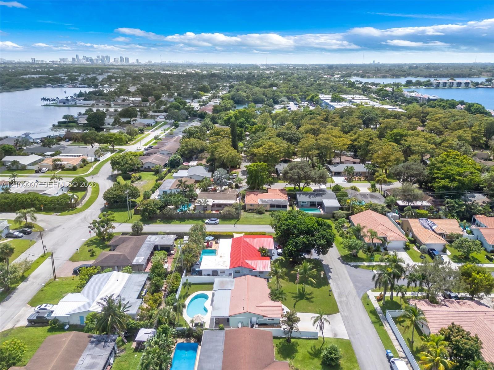 Aerial perspective featuring a residential property with a private in-ground swimming pool, metal roofing, and proximity to coastal waterways