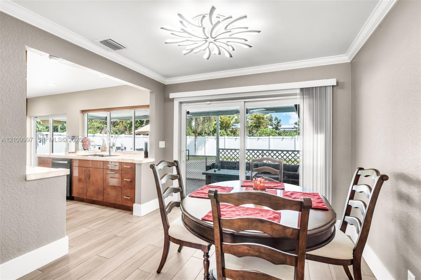 Dining area featuring wood-finish flooring, a decorative contemporary ceiling light fixture, and glass sliding doors providing exterior access