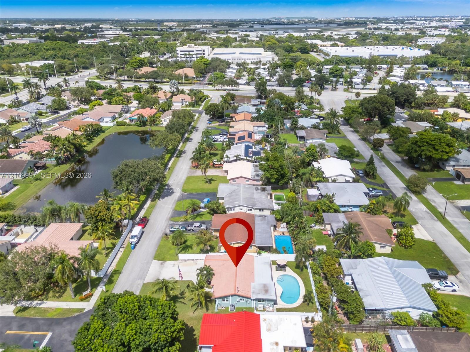 Aerial perspective featuring a single-story residence with a tiled roof, private swimming pool, fenced perimeter, and mature landscaping