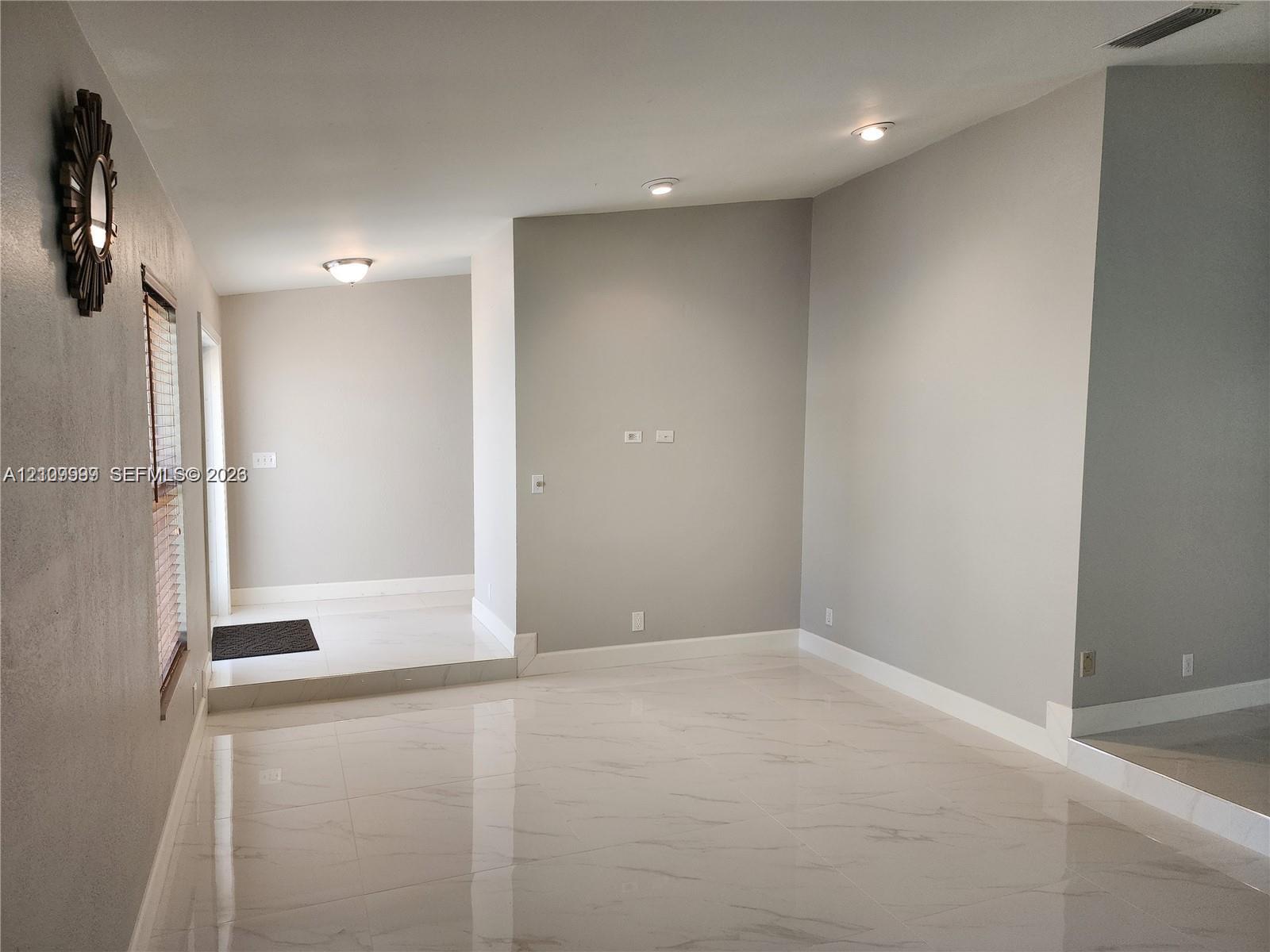 Polished neutral-toned flooring, recessed ceiling lighting, and wall-mounted fixture