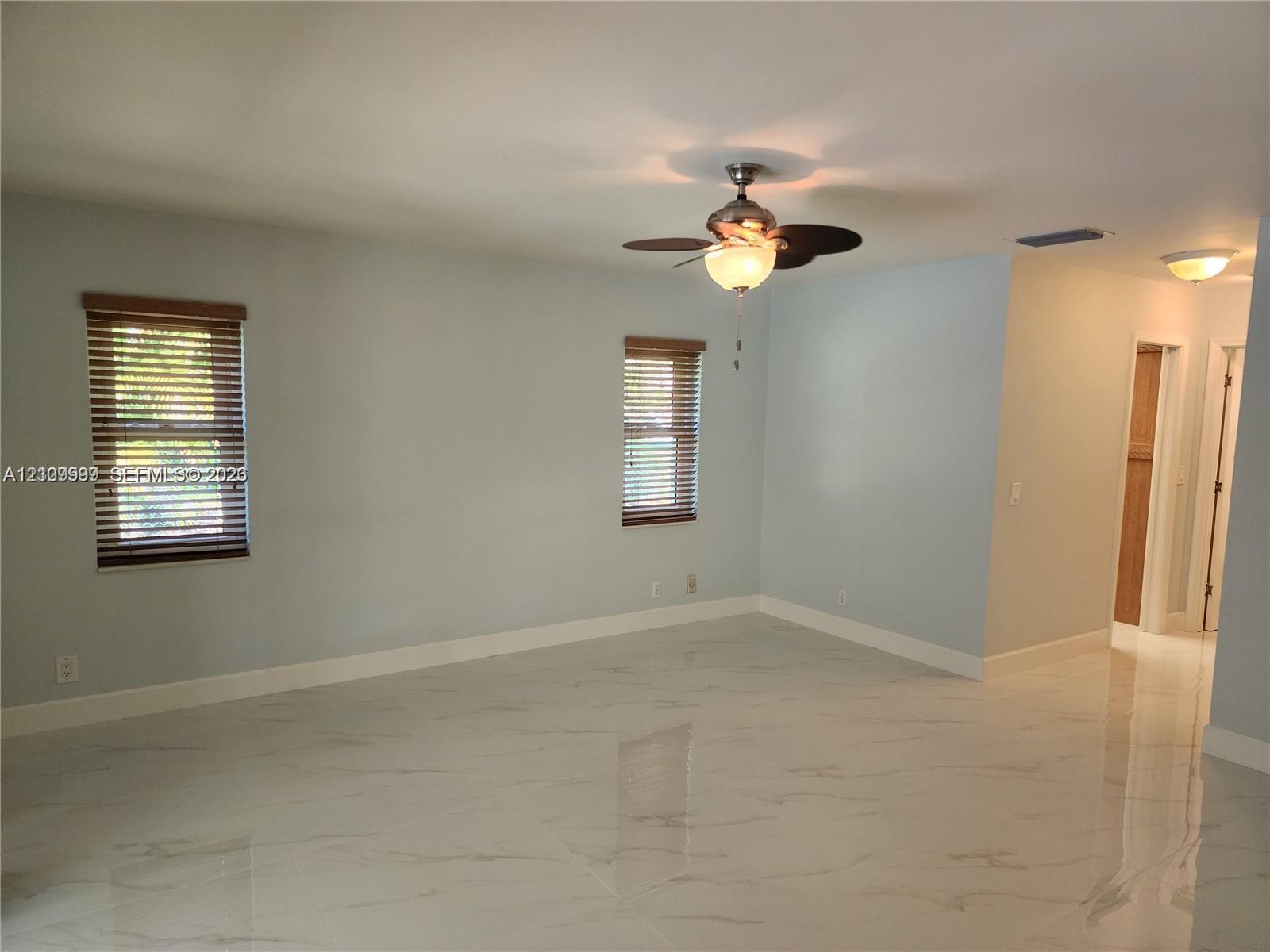 Interior space featuring polished stone-finish flooring, recessed lighting, a ceiling fan with integrated light fixture, and horizontal blinds on windows