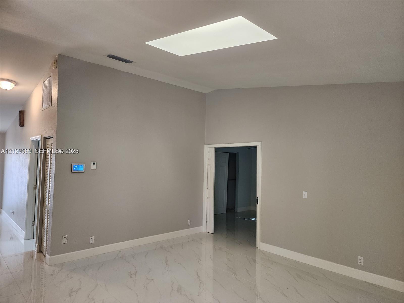 Vaulted ceilings featuring a rectangular skylight, paired with large-format stone-finish floor tiling