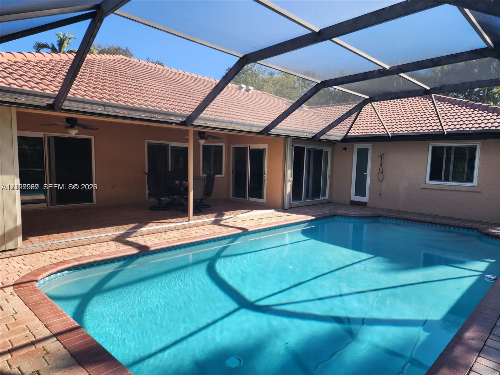 Screened lanai featuring a tile roof, paved deck, and in-ground swimming pool