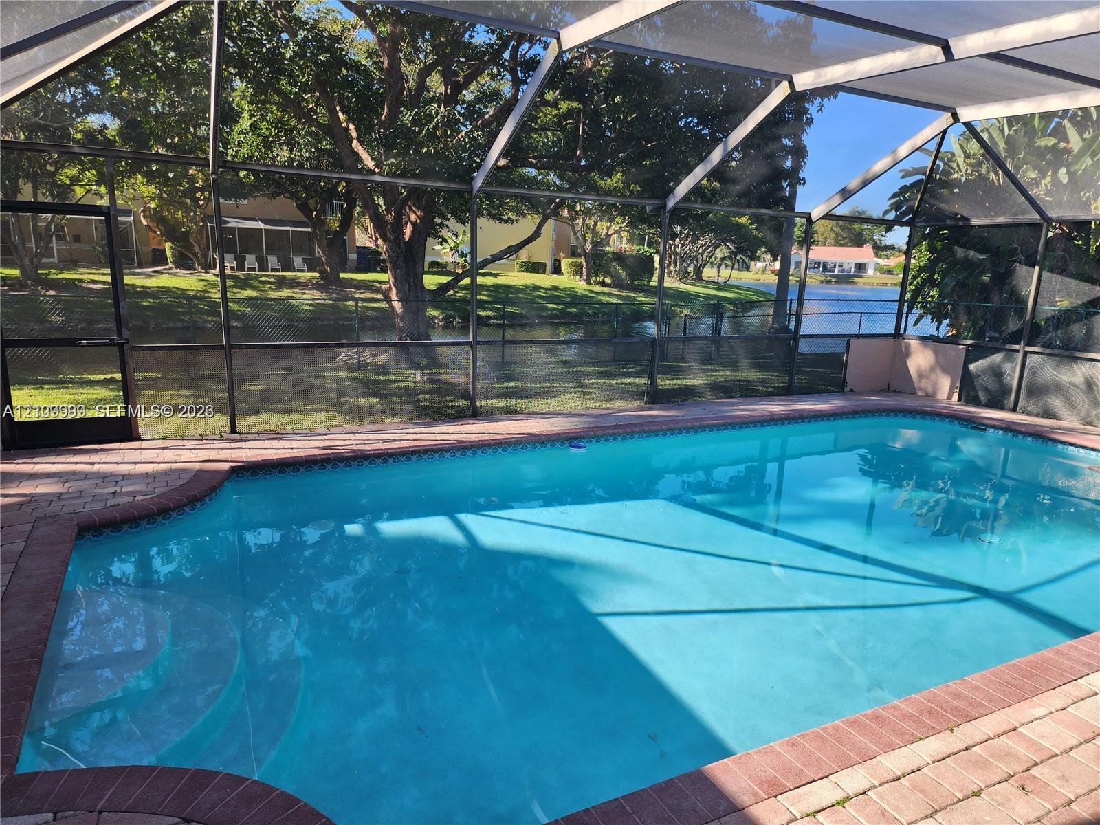 Screened-in patio featuring a swimming pool, paver deck, and waterfront access