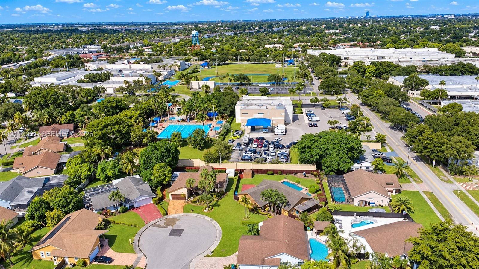 Aerial perspective of residential neighborhood featuring paved cul-de-sac streets, manicured lawns, and numerous properties with private screened-in swimming pools