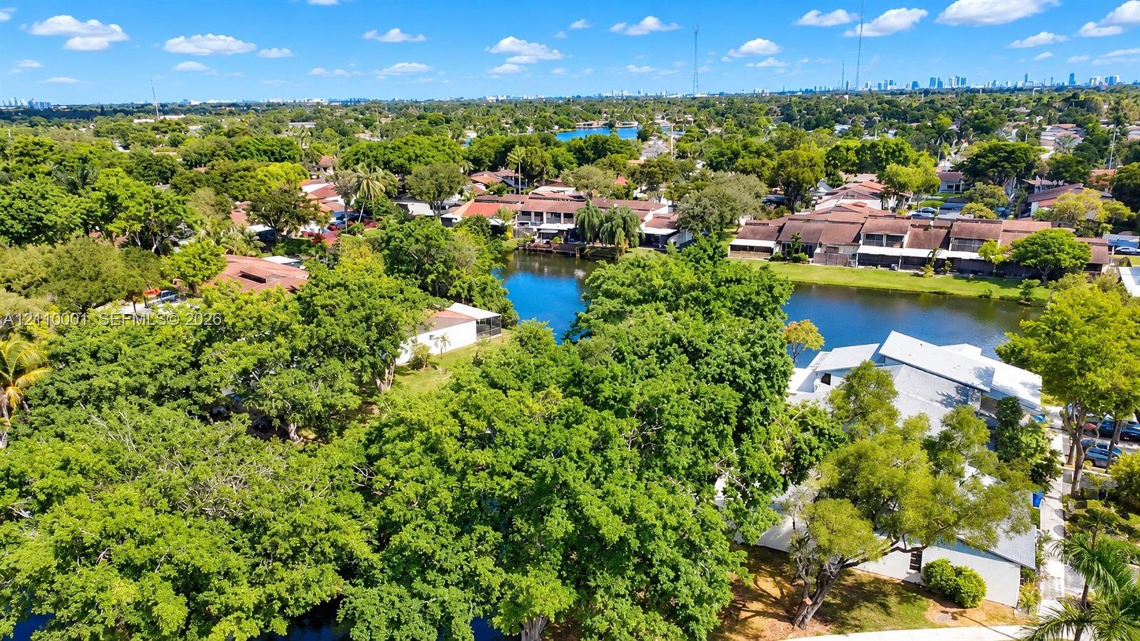 Aerial perspective featuring a waterfront setting, mature canopy trees, and established landscaping