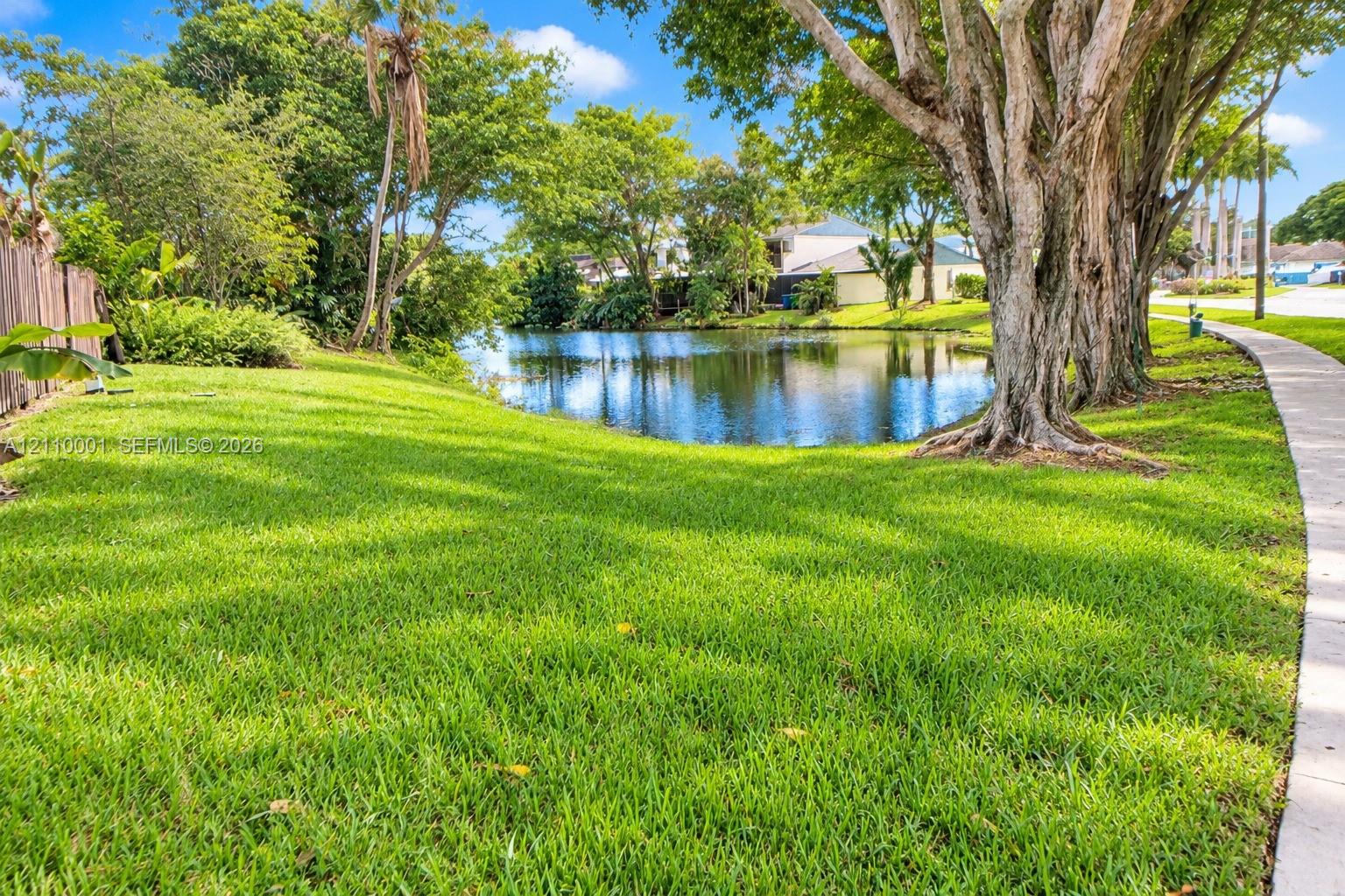 Waterfront lot featuring mature trees, expansive lawn, and concrete perimeter walkway