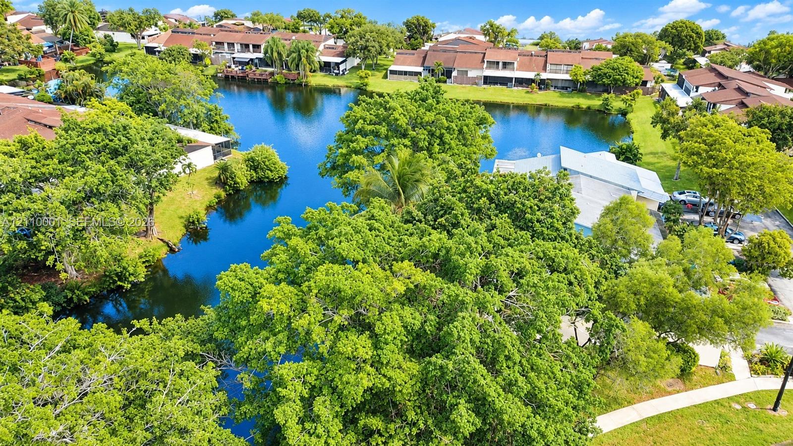 Waterfront property featuring a central lake, mature trees, and landscaped green space