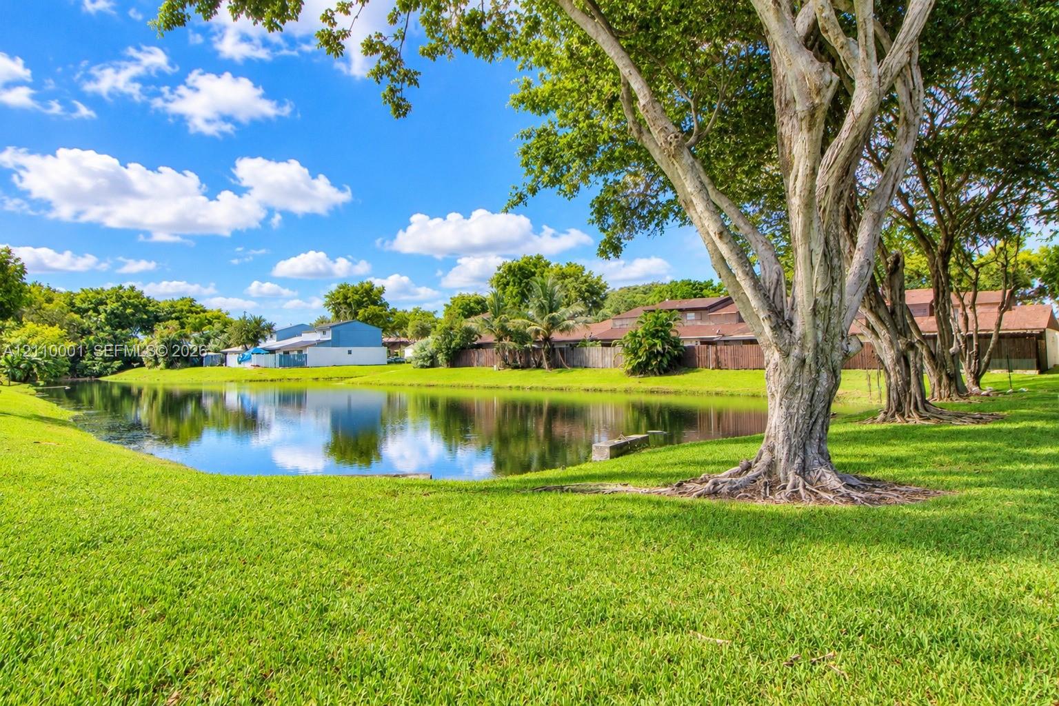 Waterfront lot featuring a manicured lawn, mature shade trees, and perimeter privacy fencing