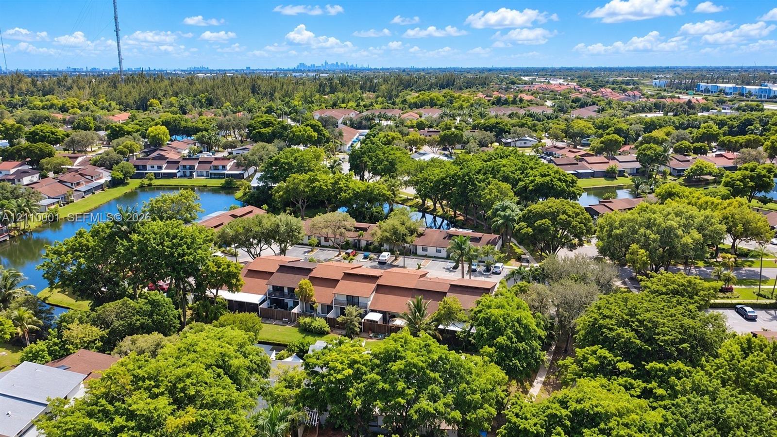 Aerial perspective featuring multi-story residential structures with pitched rooflines, mature tree canopy, and waterfront surroundings