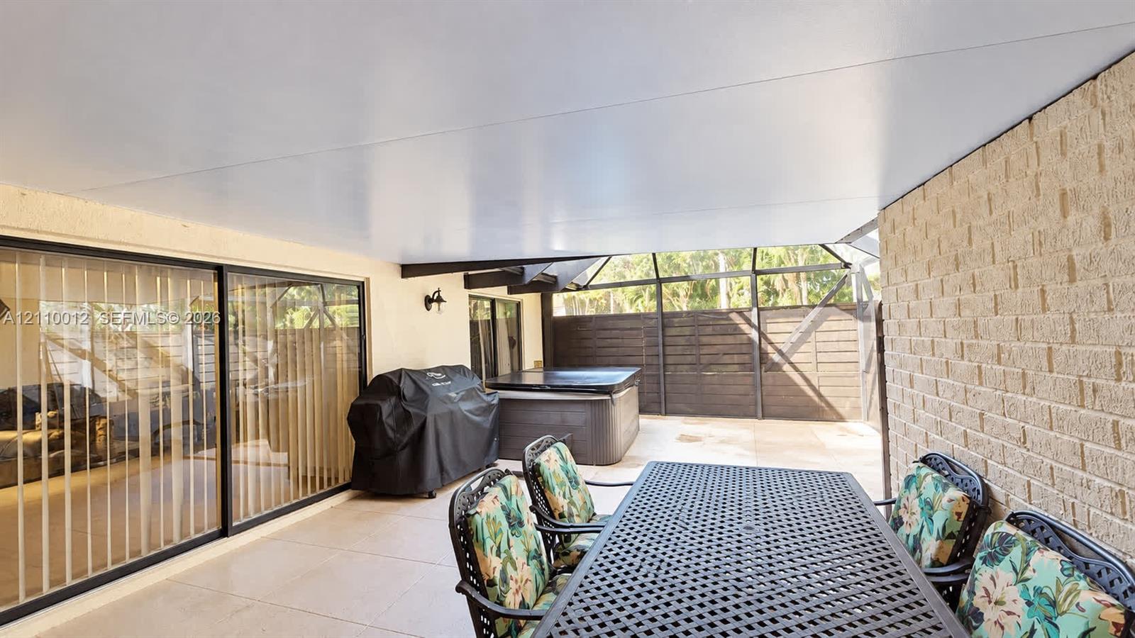 Covered patio featuring concrete tile flooring, a screen-enclosed area, and masonry exterior wall