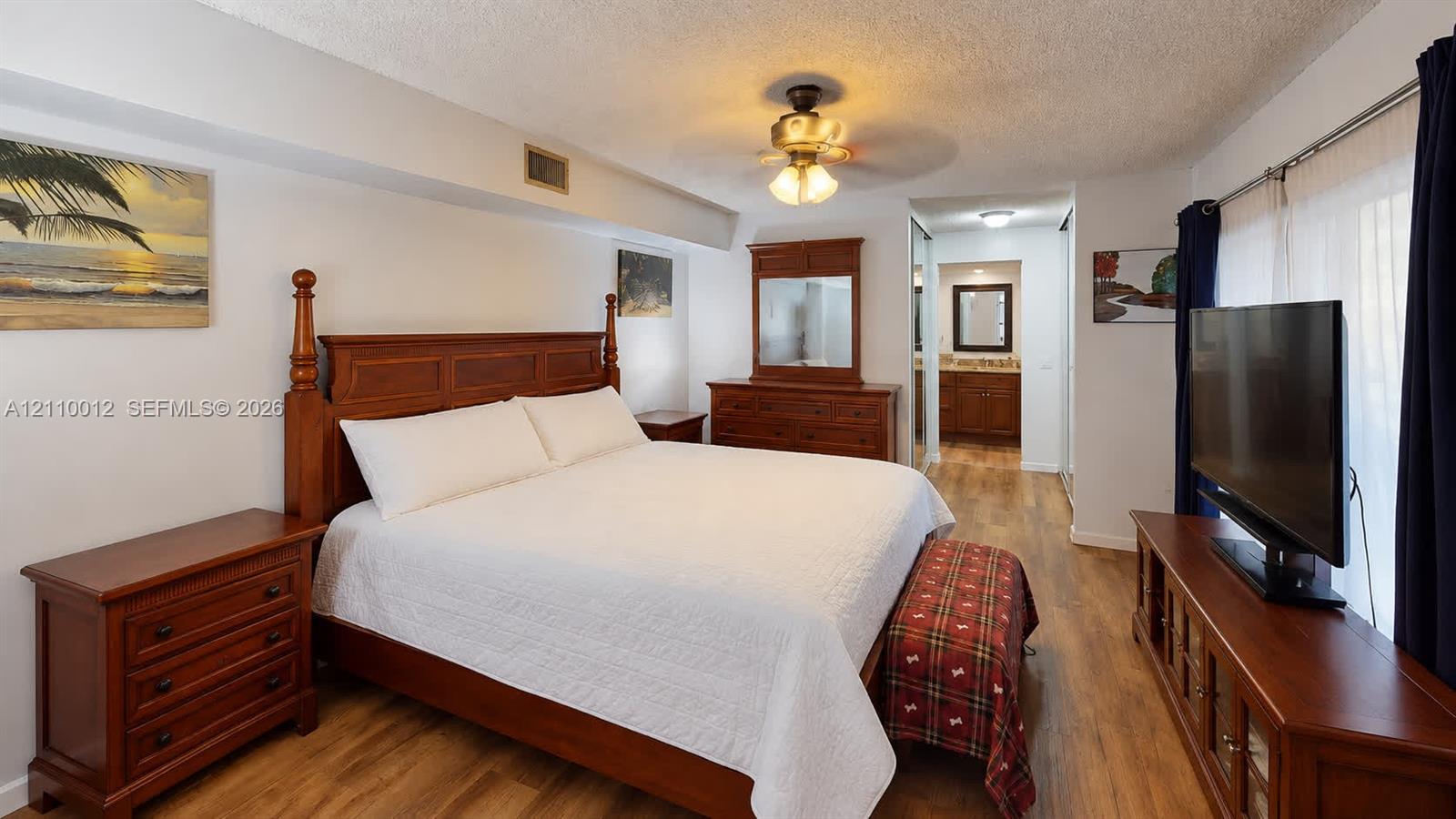 Wood-finish flooring, textured ceiling, and a central ceiling fan with multi-light fixture
