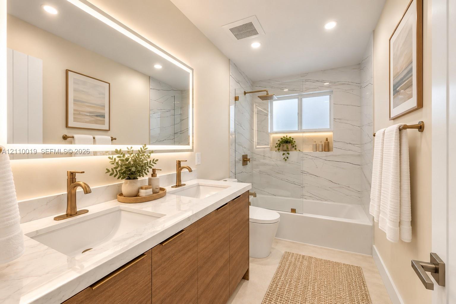 Dual-sink vanity with wood-finish cabinetry, quartz countertop, recessed lighting, integrated LED-backlit mirror, and brushed gold-tone fixtures