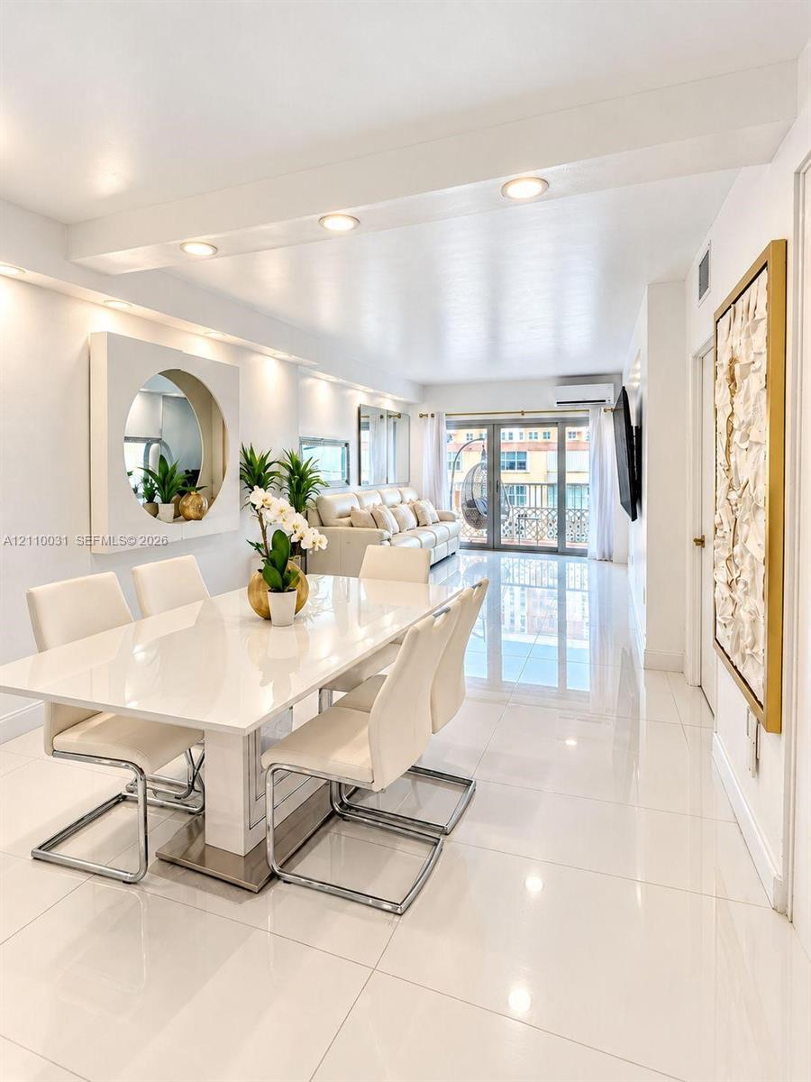 Large-format porcelain tile flooring, recessed ceiling lighting, circular wall-mounted accent mirror, and glass-paned sliding doors opening to a balcony