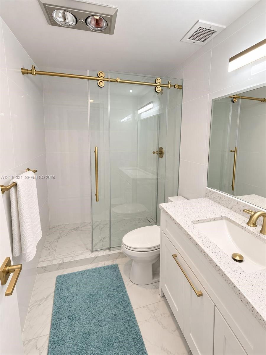 Bathroom featuring a white vanity with a speckled countertop, integrated sink, and brass-tone hardware