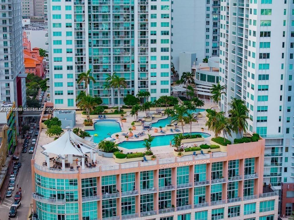 Elevated terrace featuring a multi-level swimming pool, integrated landscaping with mature palm trees, and a permanent tension-fabric shade structure