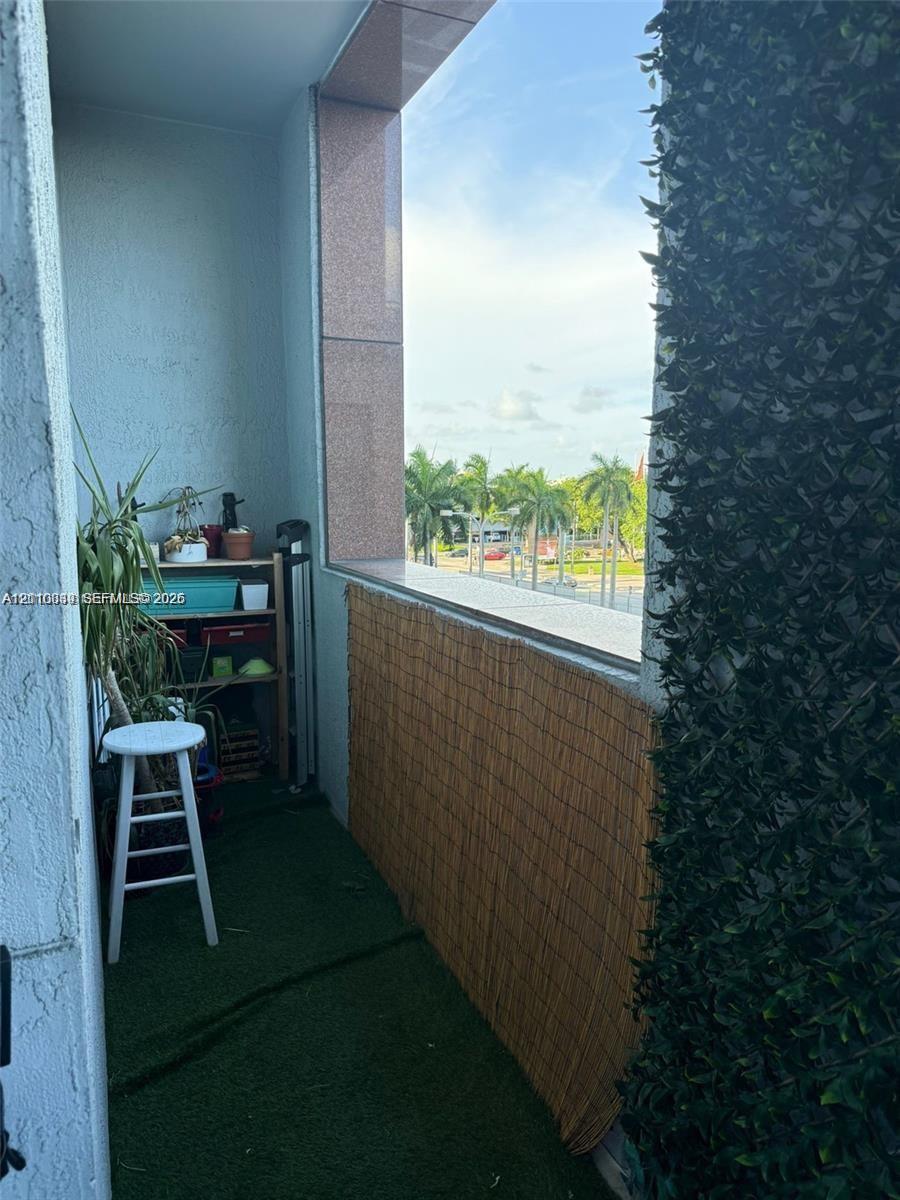 Private balcony featuring a textured stucco finish, stone-clad structural columns, and a wide ledge