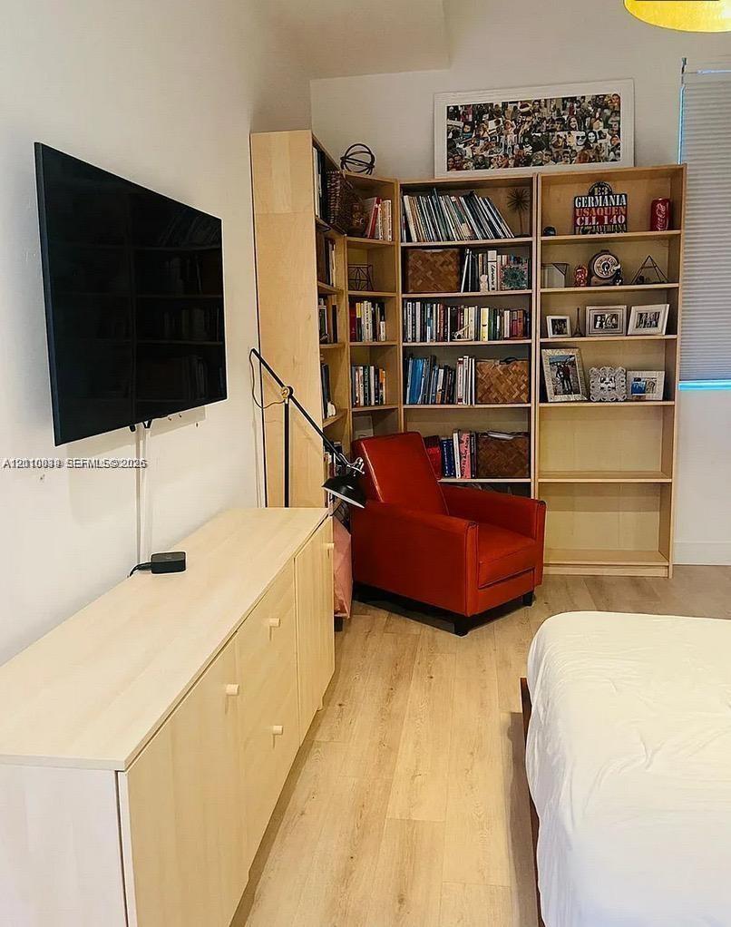 Built-in light-wood shelving unit with corner configuration, smooth wood-finish flooring, and wall-mounted television console with cabinets
