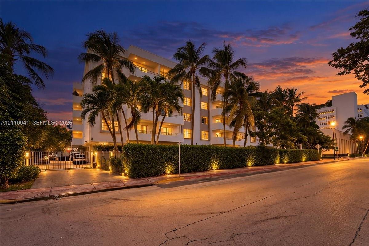 Multi-story residential building featuring private balconies, integrated landscape lighting, and a gated entrance