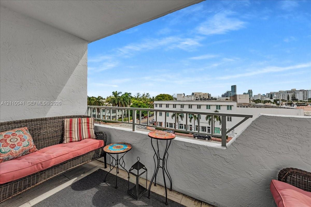 Covered balcony featuring textured stucco walls and a metal railing