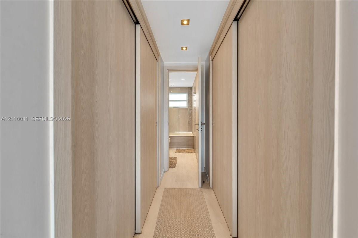Hallway featuring floor-to-ceiling wood-finish sliding doors, recessed lighting, and wood-finish flooring