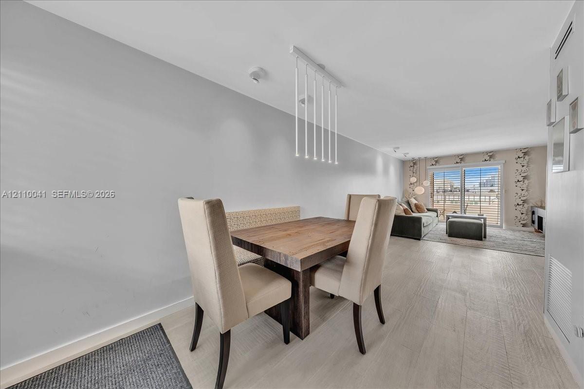 Open floor plan featuring wood-finish flooring, a contemporary linear pendant light fixture, and sliding glass doors with direct access to an exterior deck