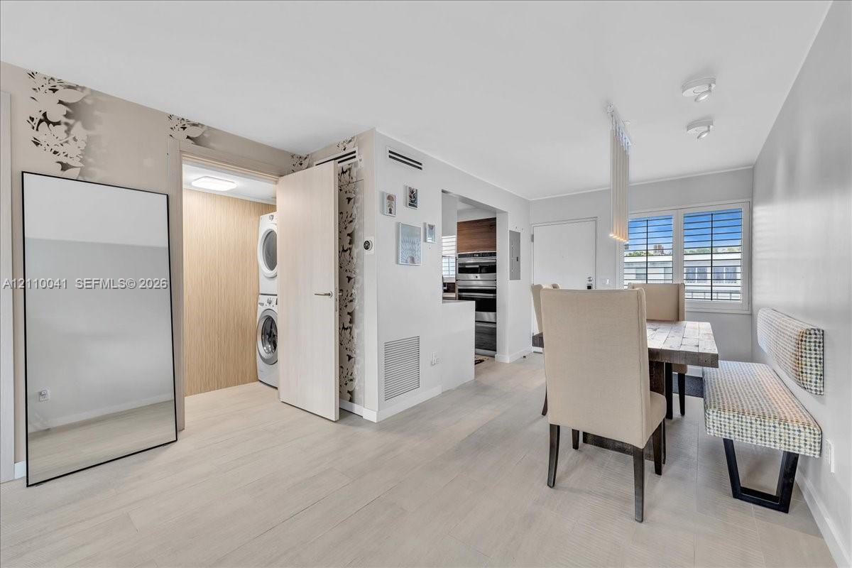 Light-toned wood-finish flooring, dedicated laundry closet with stackable appliances, recessed ceiling lighting, and windows with horizontal blinds