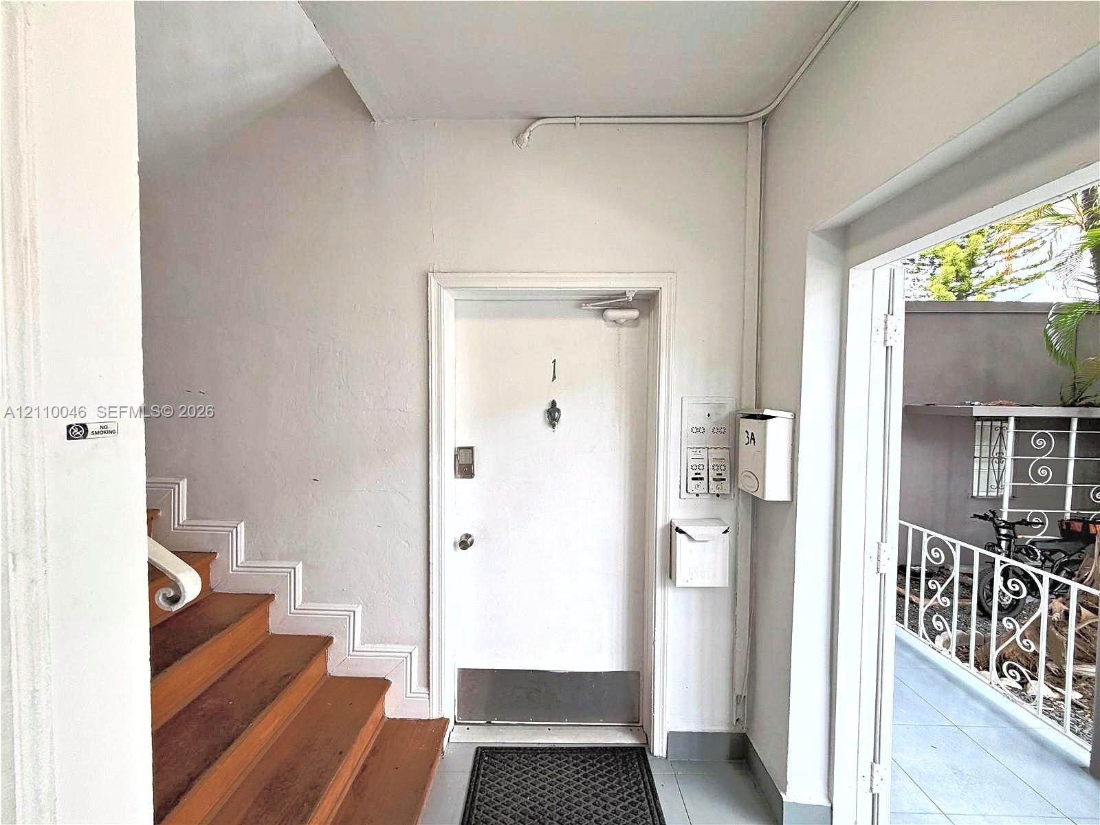 Entryway featuring a solid door with a metal kick plate and viewer, wooden stairs, integrated mailboxes, and an exterior balustrade