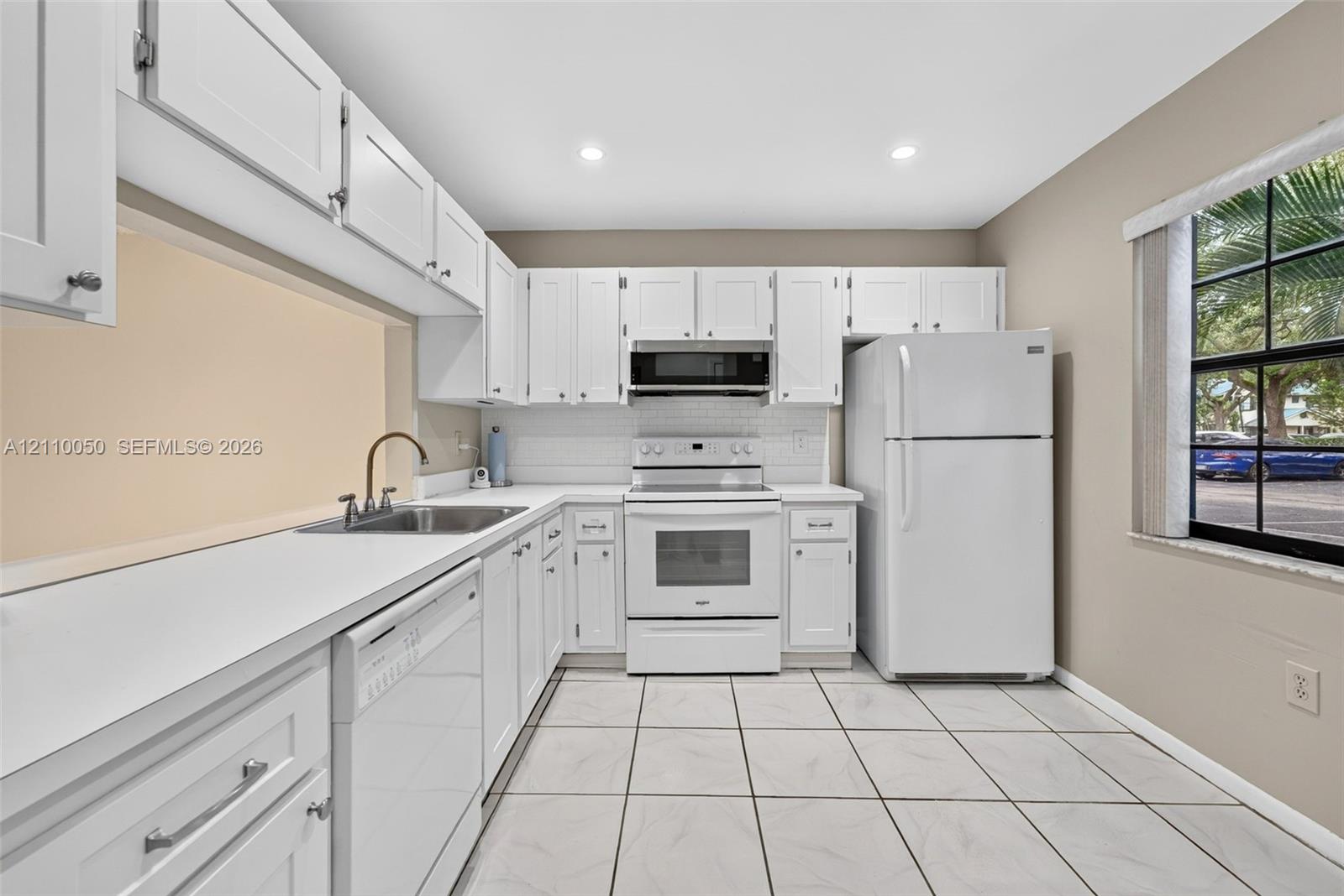 Kitchen featuring white shaker-style cabinetry, white solid-surface countertops, subway tile backsplash, recessed lighting, and tile flooring
