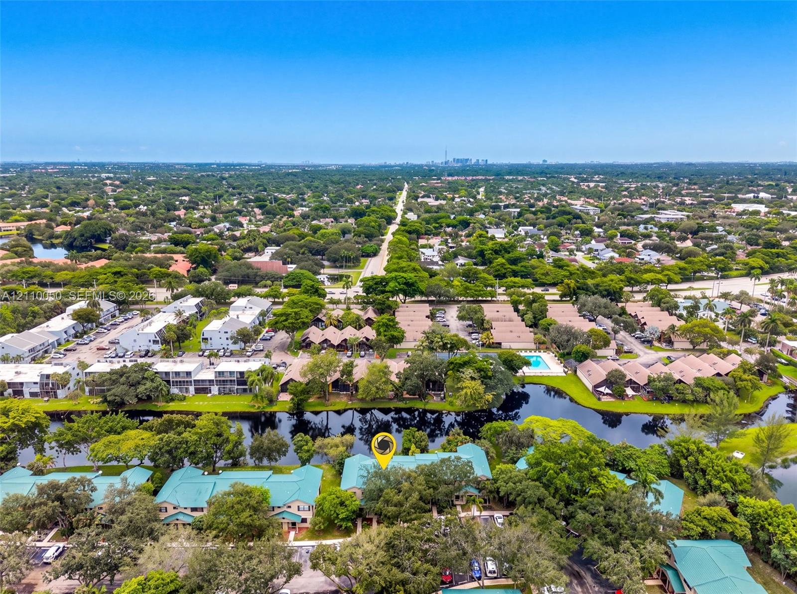 Aerial perspective of the property featuring waterfront positioning, expansive tree canopy coverage, and multi-building complex layout