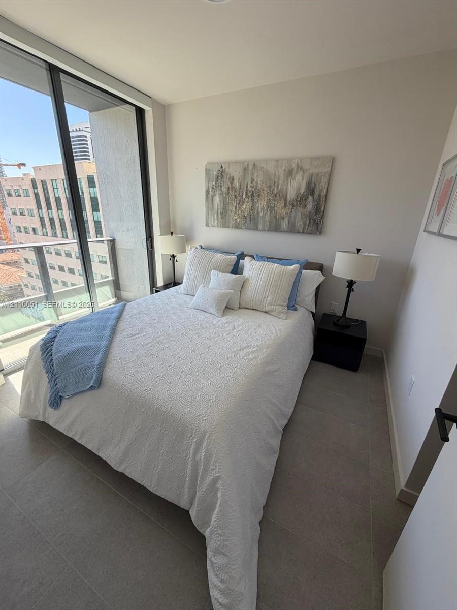 Floor-to-ceiling glass sliding door, balcony access, and large-format tile flooring