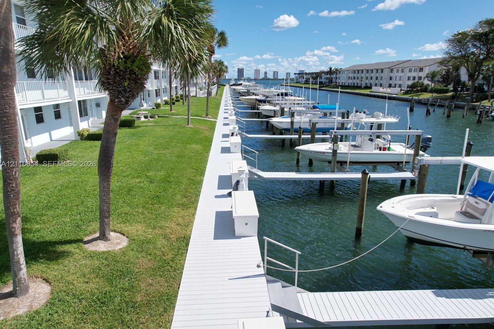 Waterfront property featuring a private multi-slip dock, composite decking, manicured lawn, and mature palm trees