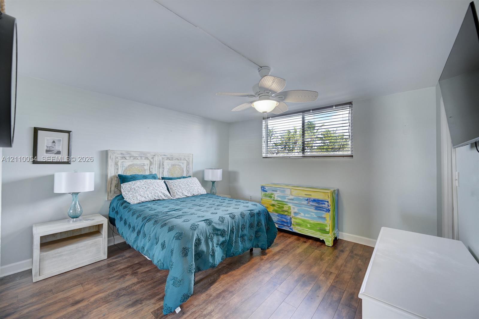 Wood-finish flooring, ceiling fan with integrated lighting, and window with horizontal blinds