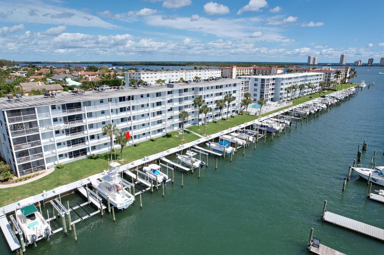 Waterfront condominium complex featuring a private dock system, direct deep-water access, multi-level balconies, and manicured landscaping